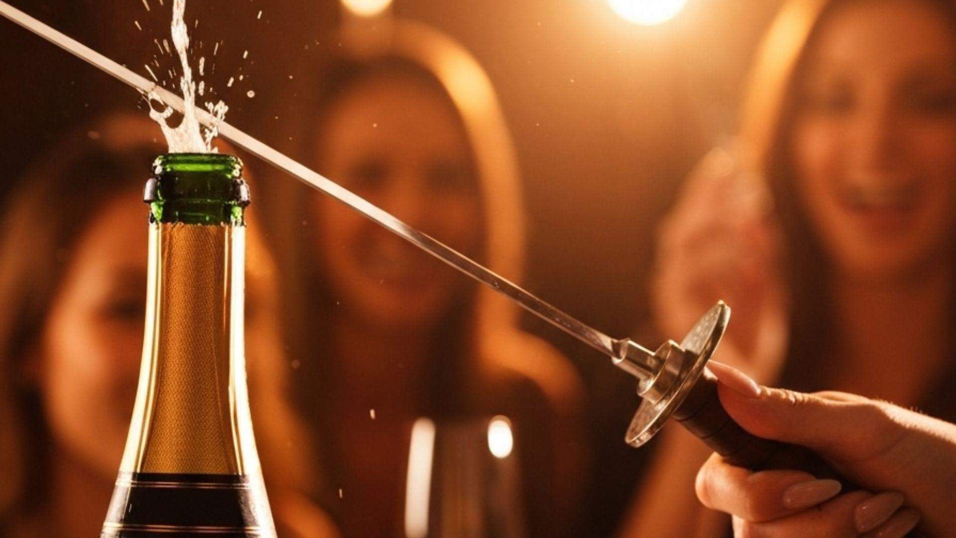 Hånd der åbner en champagneflaske med en sabel ved en fest
