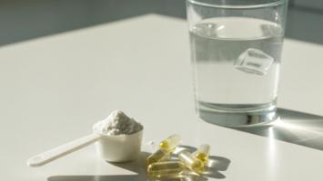 Kreatin pulver, kapsler og glas vand på lys køkkenbordplade