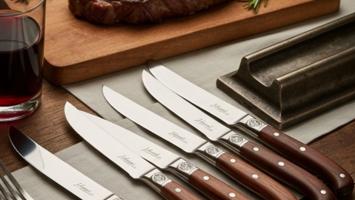 Sæt af elegante Laguiole-steakknive med træskaft på et træbord